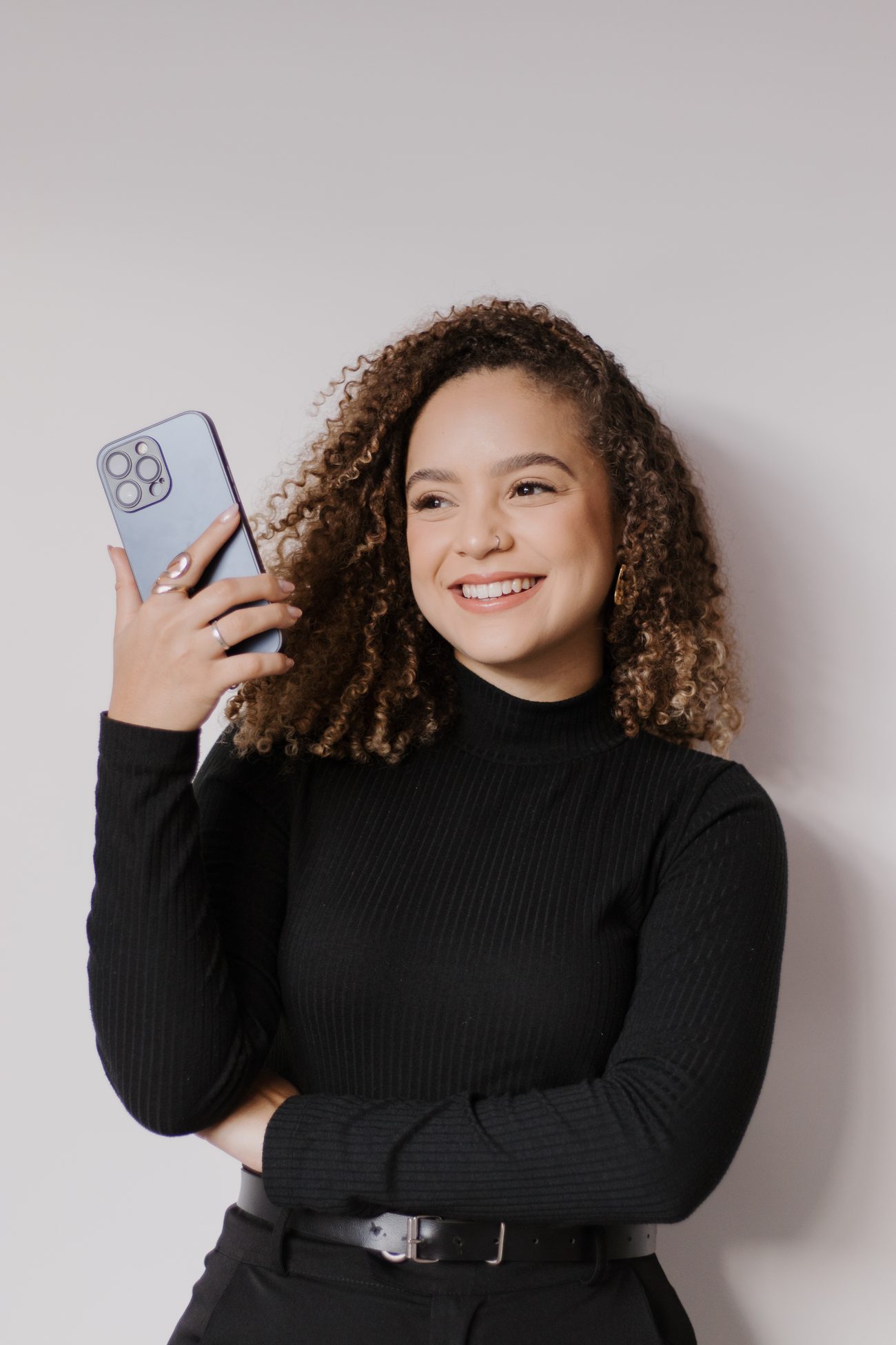 Wesliaine, fundadora da AINÊ STUDIO, segurando o celular